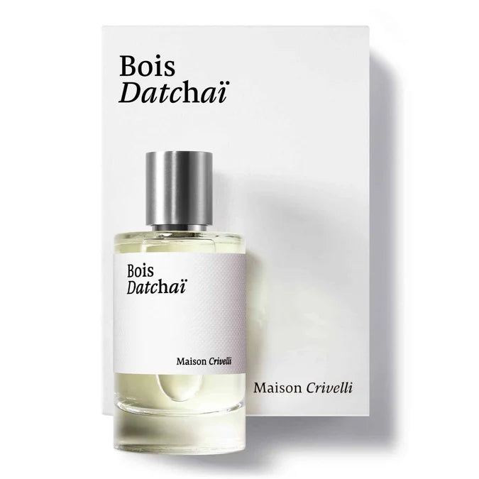 A 100ml cylindrical glass bottle of Maison Crivelli Bois Datchaï Eau De Parfum with a brushed silver cap, standing in front of its clean, oversized white presentation box featuring elegant black serif typography.